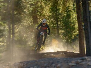 A mountain biker takes flight on a downhill course in the woods.