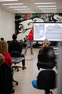 Presenter standing in front of audience with slideshow