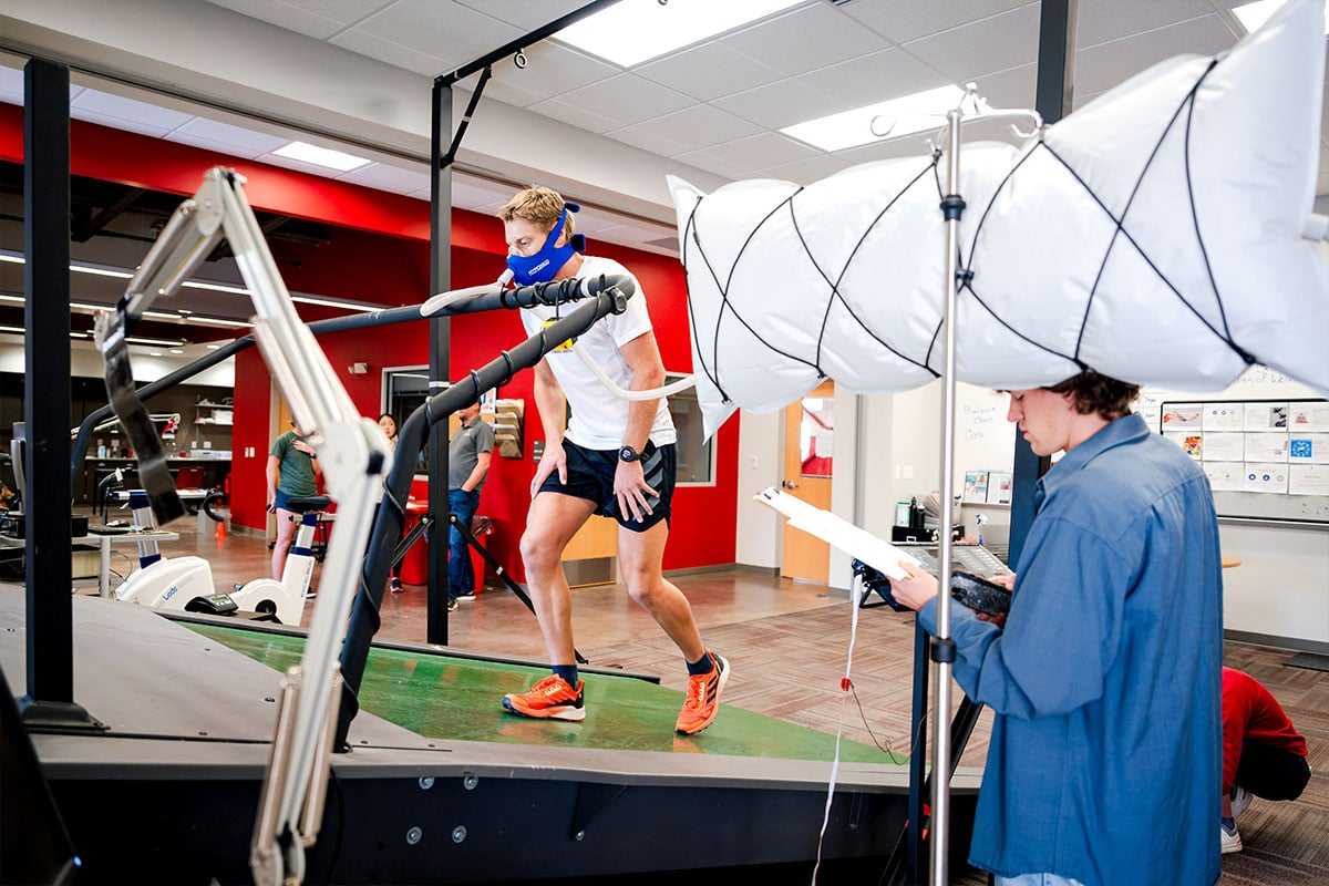 Student wearing a face mask as he walks on an inclined treadmill inside the HAP Lab