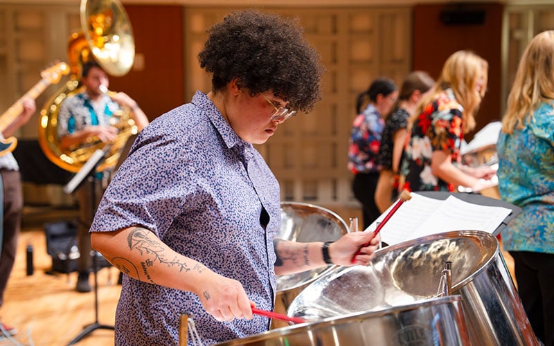 Student playing a steel pan during a steel band practice