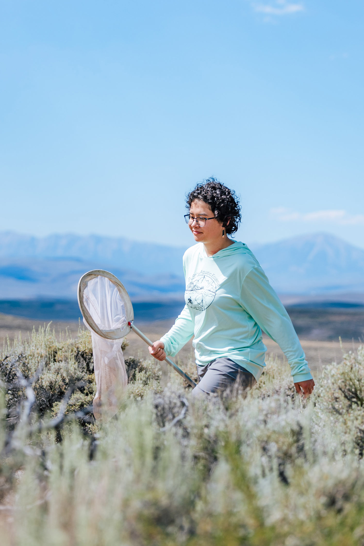 Student walking down a dirt road holding a butterfly net