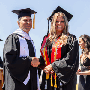 Taylor Hubbard shakes hands with President Brand Baca on the stage at commencement.