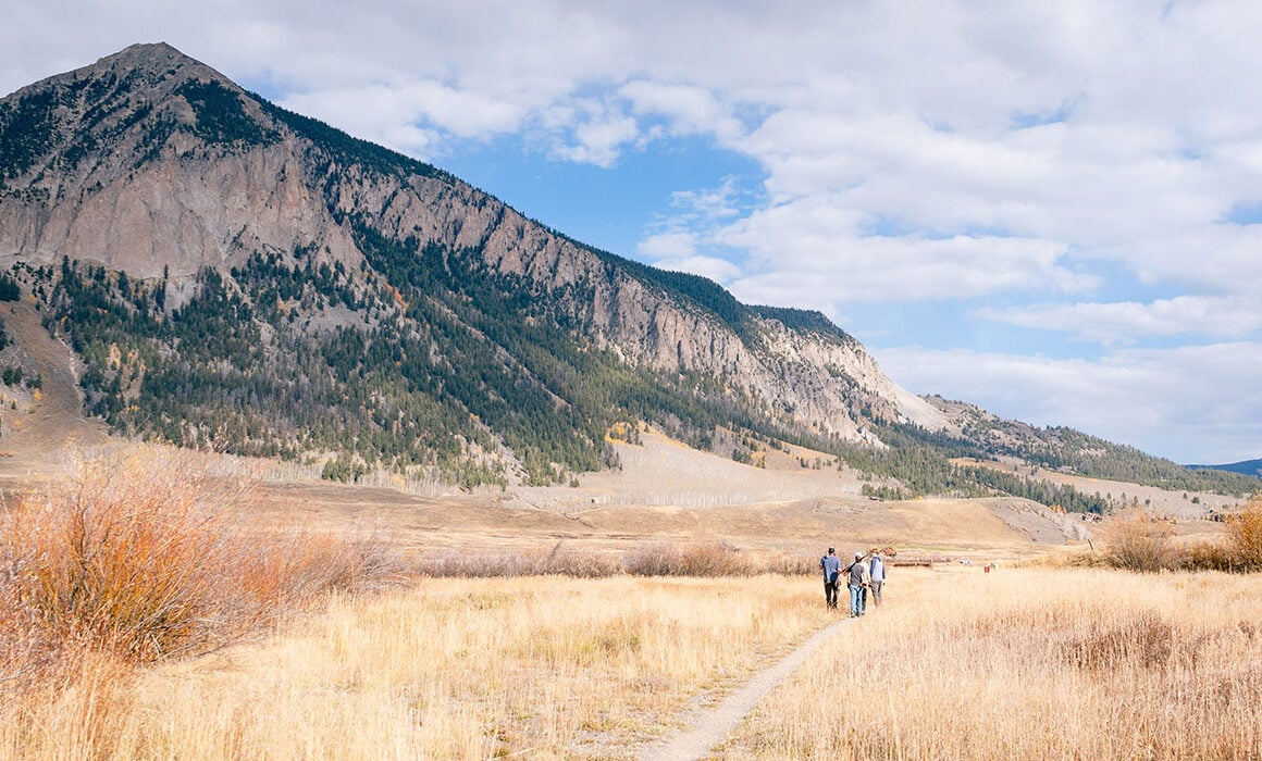 Four students walk along a trail at Verzuh Ranch with Mt. CB in the background