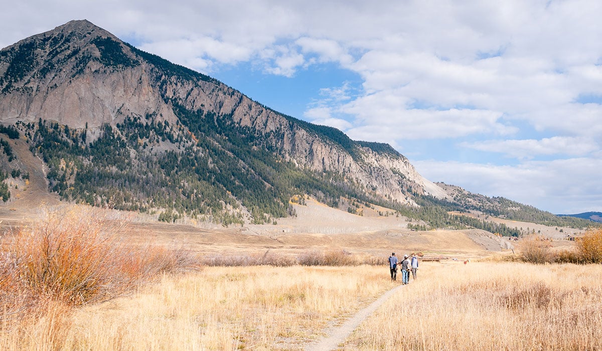 Four students walk along a trail at Verzuh Ranch with Mt. CB in the background
