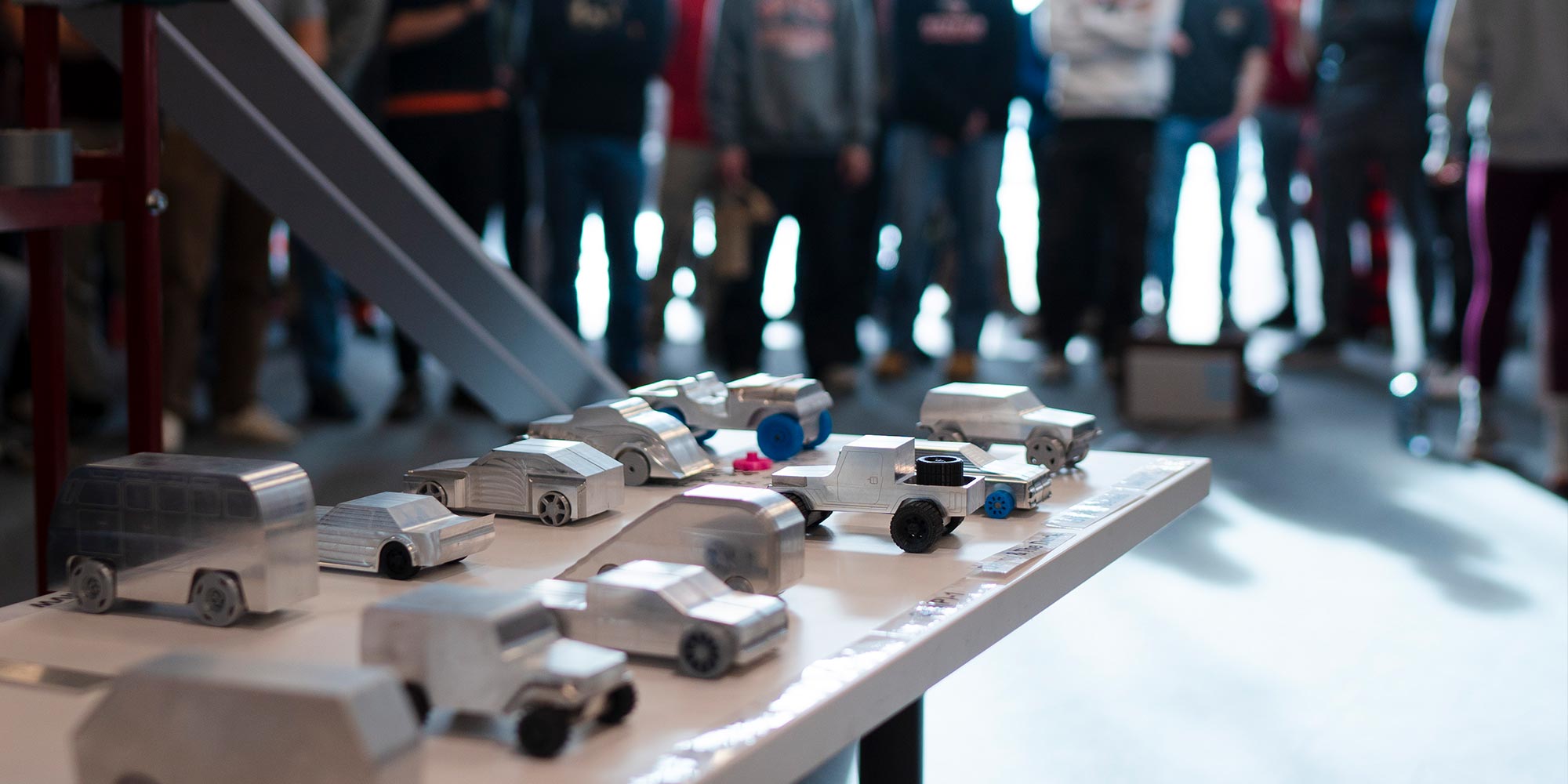 Toy sized cars on a table made of metal that students made for a project