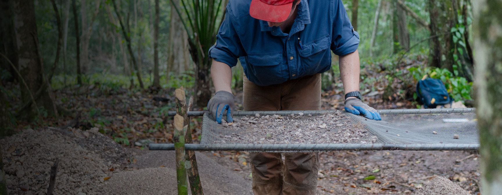 A student sifts through small rocks and sediment to check for artifact pieces during the Maya Archaeological Field School in Belize.