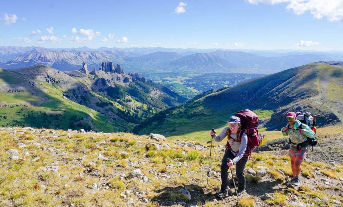 Two students smile at the top of Storm Pass while on a backpacking trip.