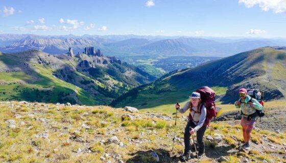 Two students smile at the top of Storm Pass while on a backpacking trip.