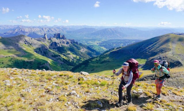 Two students smile at the top of Storm Pass while on a backpacking trip.