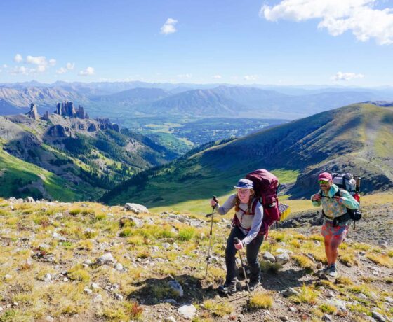 Two students smile at the top of Storm Pass while on a backpacking trip.