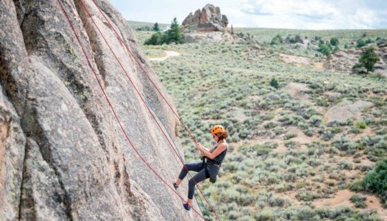 A student rappels down a rock face at Hartman Rocks.