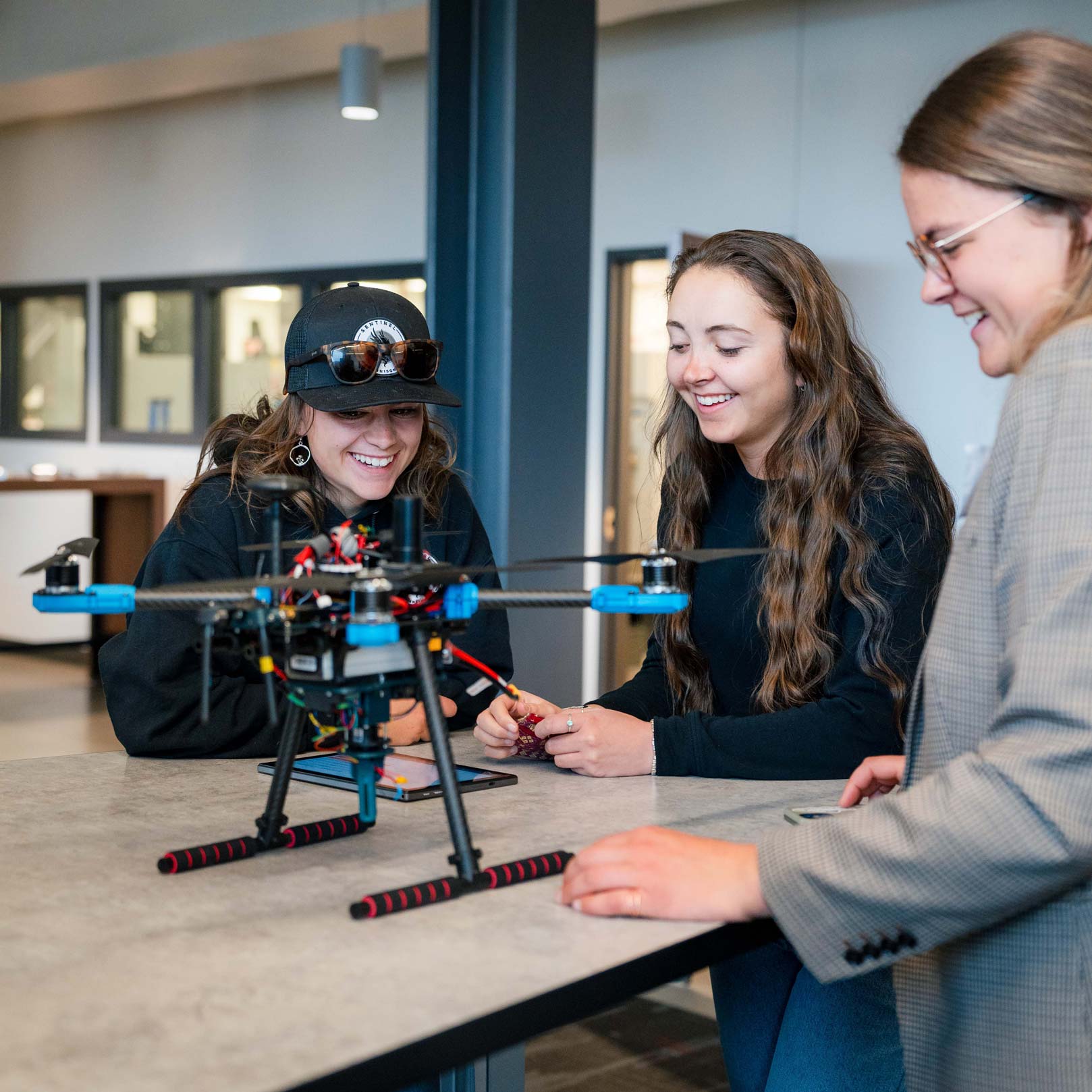 3 girls stand around a drone on a table during Industry Night