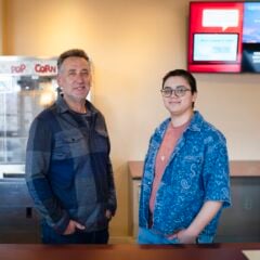 Photo of Film faculty, Julian Rubenstein, and student manager, Reed Juarez Welsh, standing behind the counter at the Mountaineer Cinema,