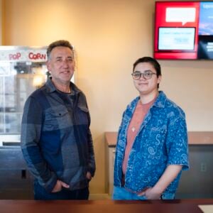 Photo of Film faculty, Julian Rubenstein, and student manager, Reed Juarez Welsh, standing behind the counter at the Mountaineer Cinema,