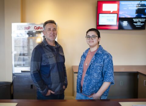 Photo of Film faculty, Julian Rubenstein, and student manager, Reed Juarez Welsh, standing behind the counter at the Mountaineer Cinema,