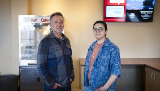 Photo of Film faculty, Julian Rubenstein, and student manager, Reed Juarez Welsh, standing behind the counter at the Mountaineer Cinema,