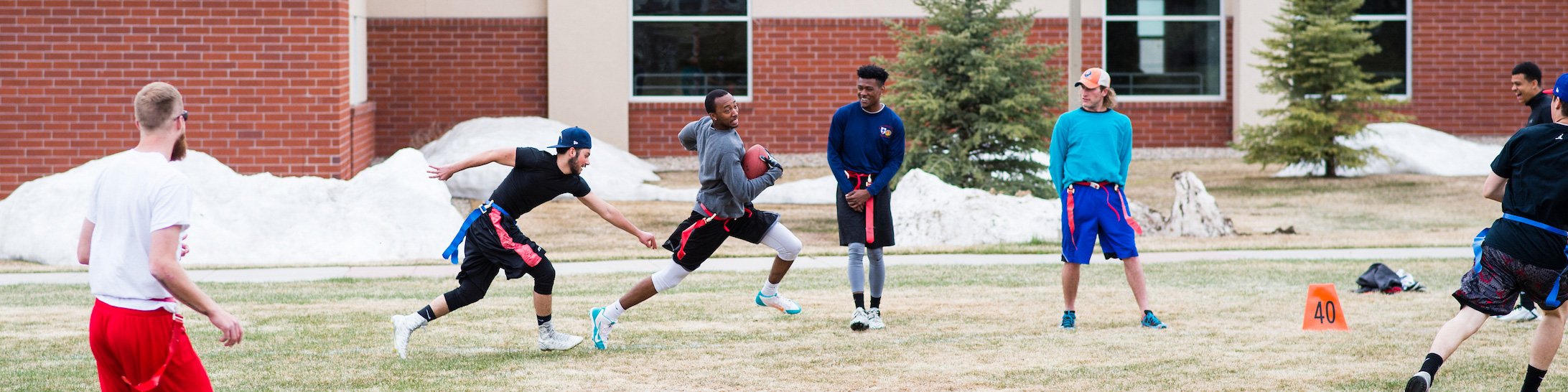 Students play flag football on the lawn outside the Mountaineer Field House.