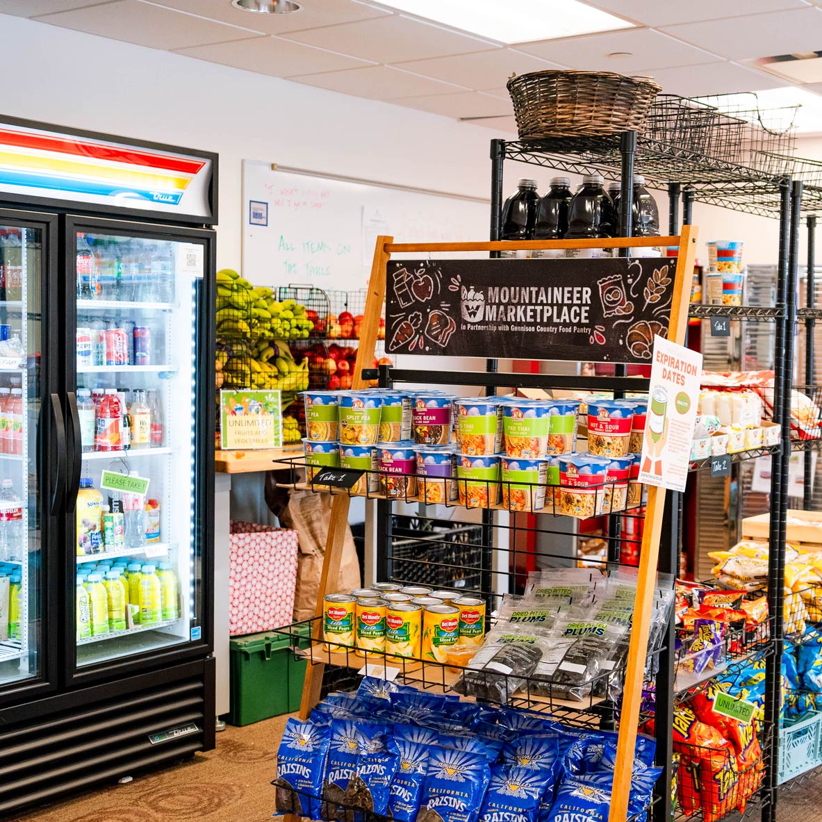 The interior of the Mountaineer Marketplace with a fridge, cabinets, and shelves full of food.