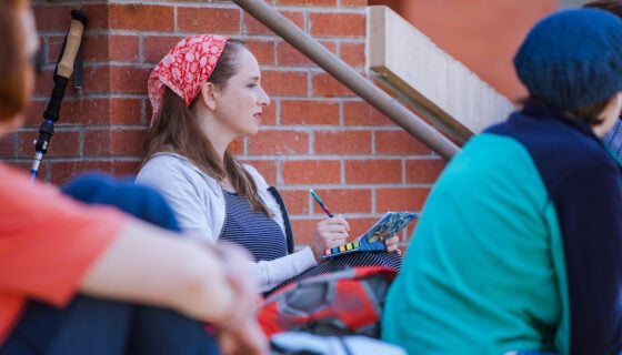 A student sits on the steps of Taylor Hall and takes notes during a lecture.