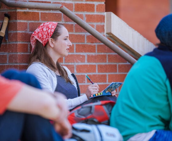A student sits on the steps of Taylor Hall and takes notes during a lecture.