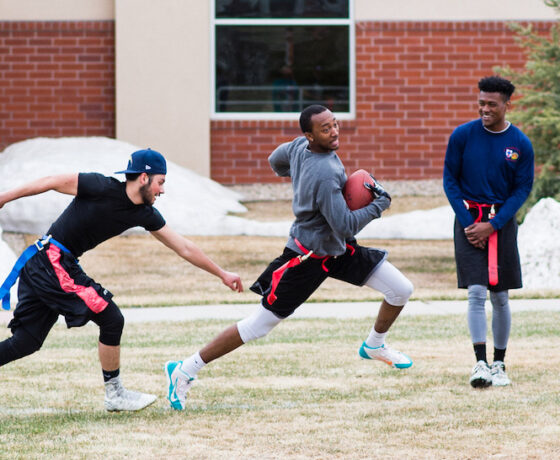 Students play flag football on the lawn outside the Mountaineer Field House.