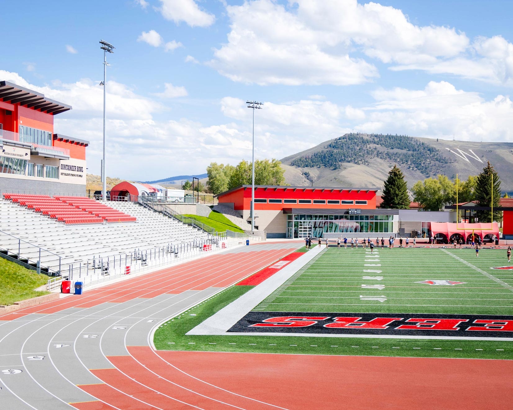 On a hill looking down at the Mountaineer Bowl's field, track, and grandstands with W Mountain in the background.