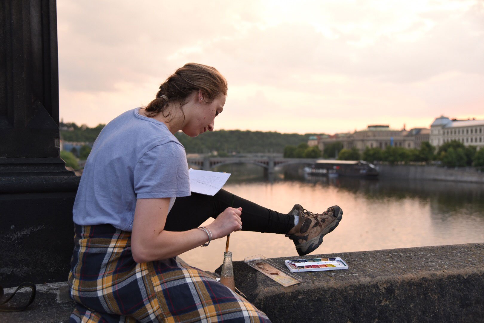 A student watercolor paints a sunset in Prauge.