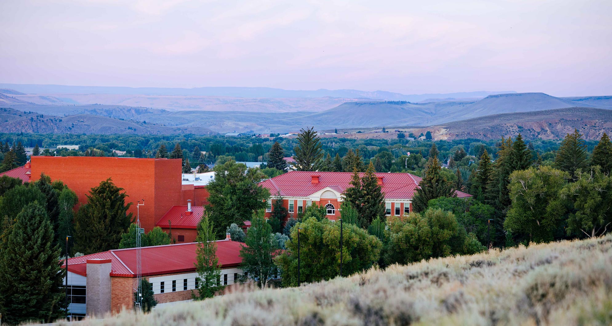 Taylor Hall and Hurst Hall at sunrise with mountains in the background.