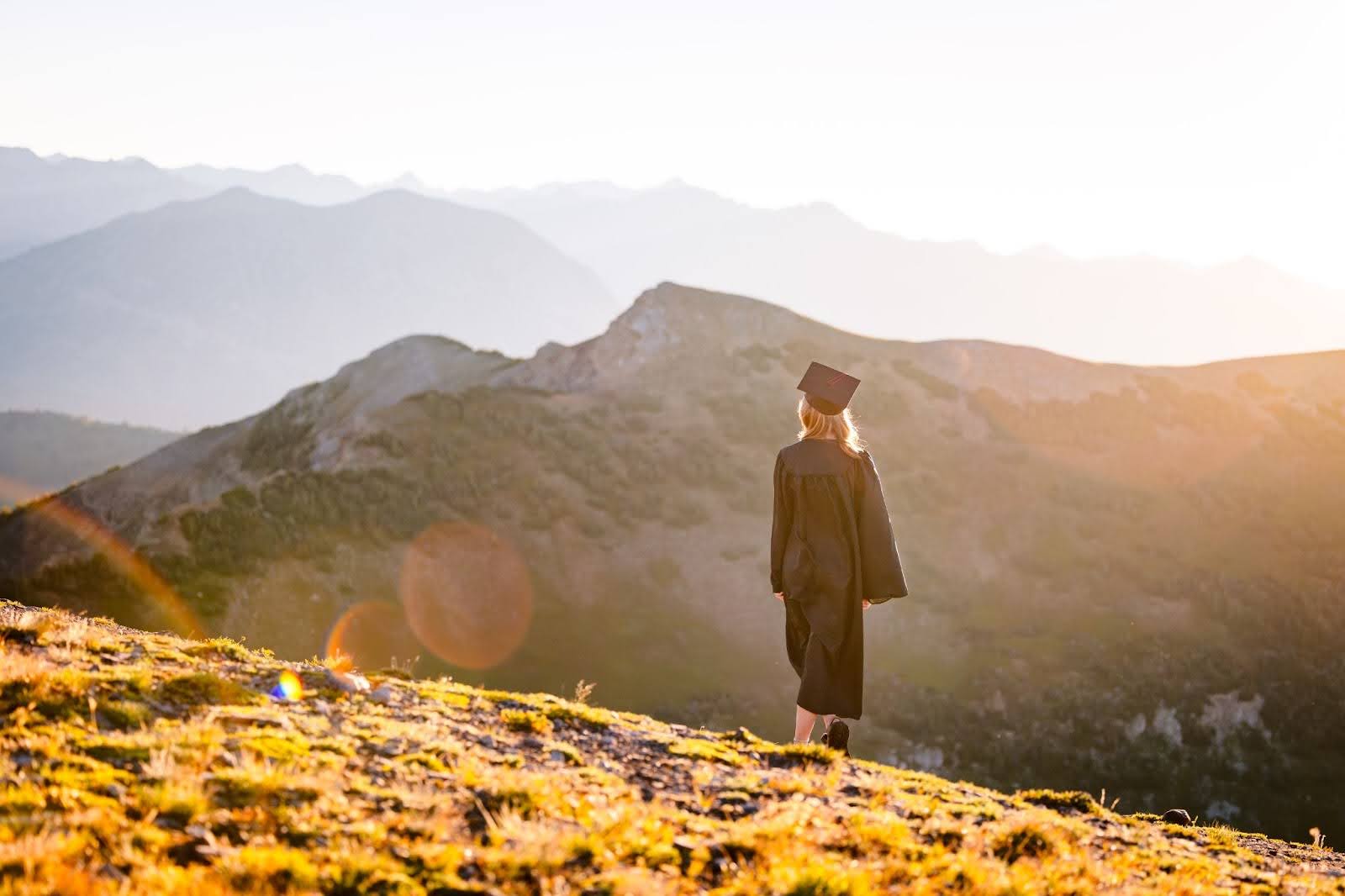 Student in grad gear walking on mountains