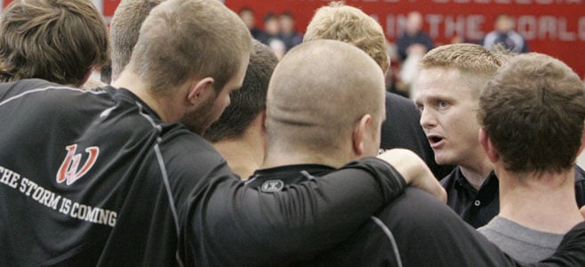 Miles VanHee talks with athletes in a huddle.