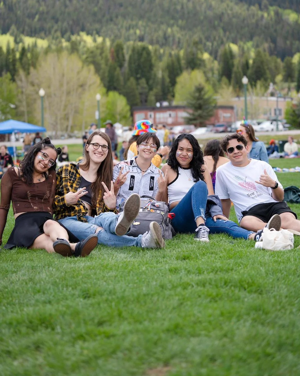 A group of students gather together on the grass.