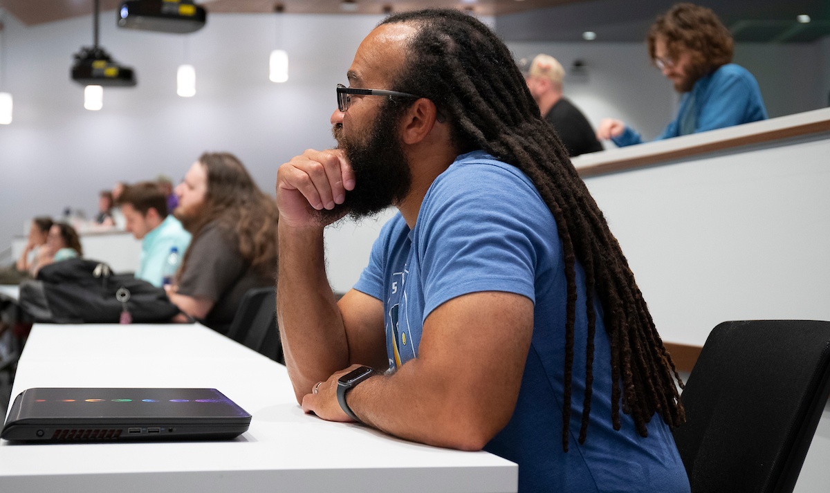 Student sits at desk in a classroom as he listens to a lecture.