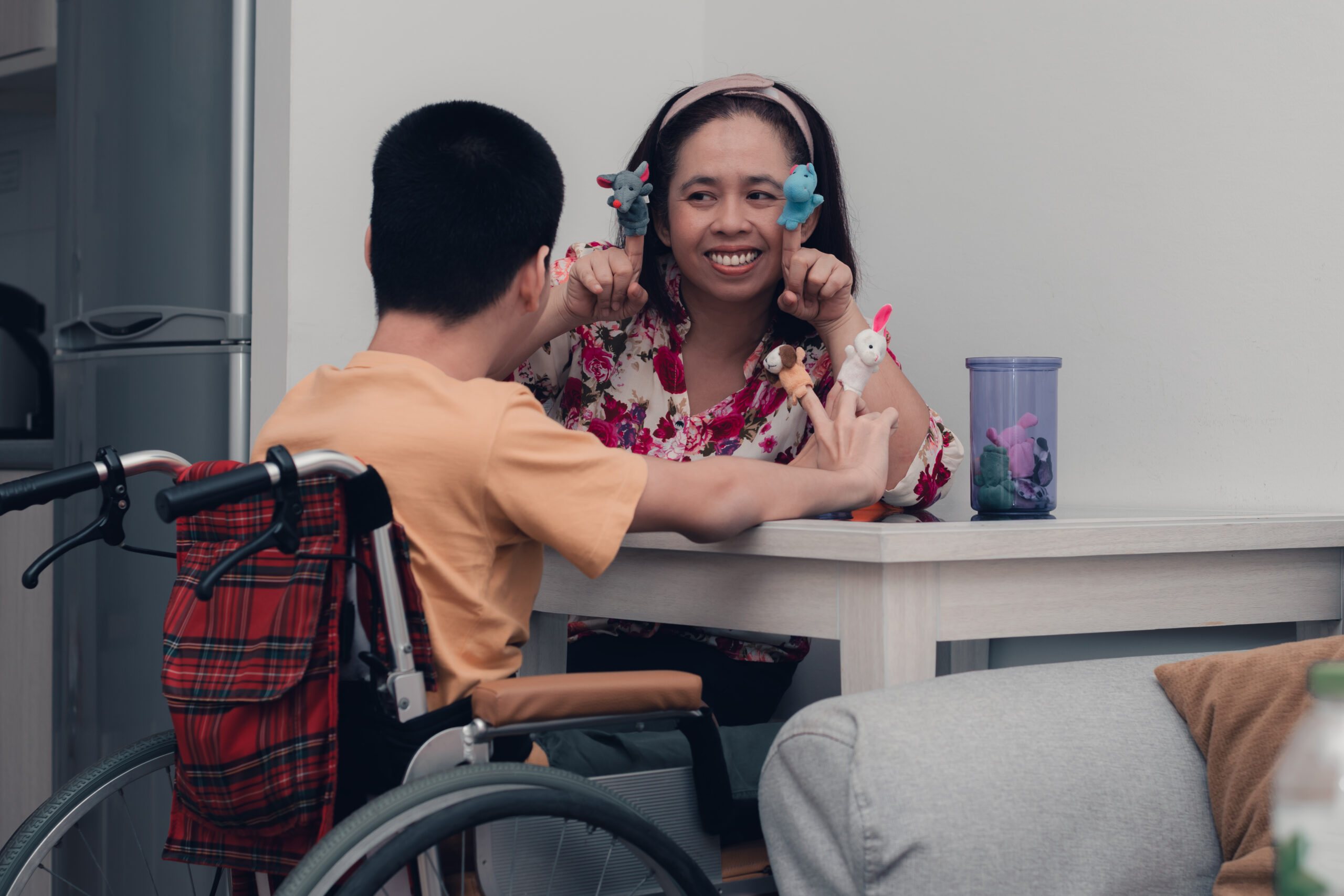 A female student teacher demonstrates a lesson for a student in a wheelchair.