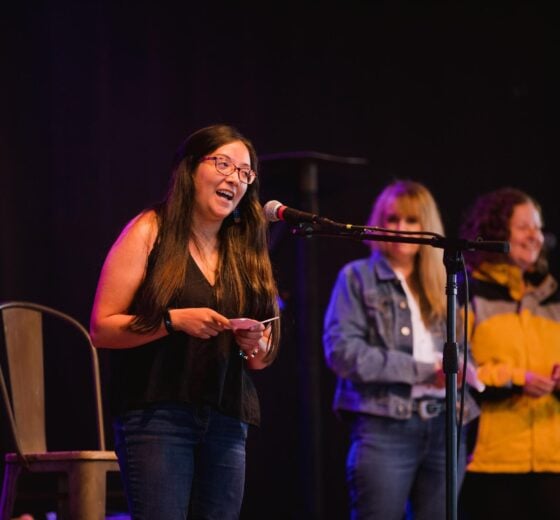 A student on stage speaking into a microphone.
