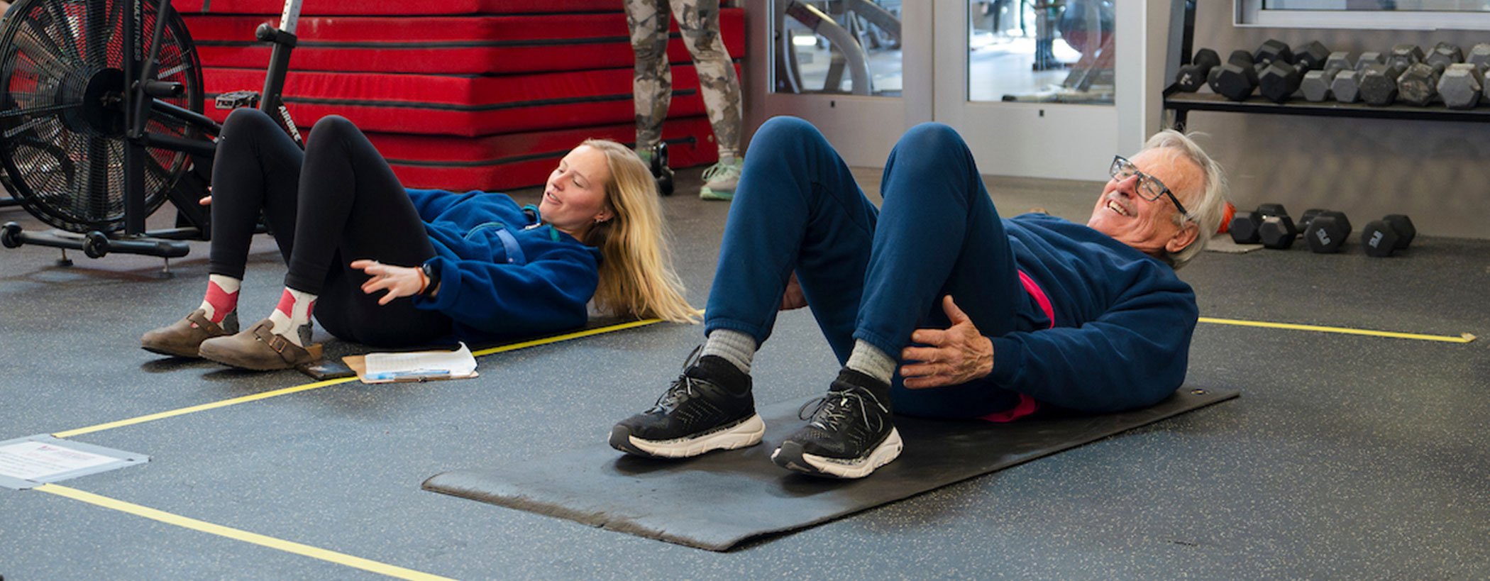 A student with the Wellness Elevated program coaches a community member through stretches and exercises at the Mountaineer Field House.