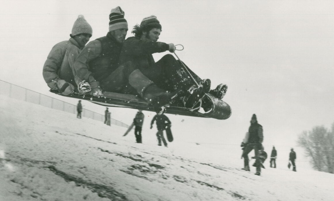 Three Western students catch some air on their toboggan on the way down College Hill, 1970s.