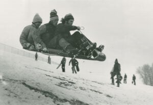 Three Western students catch some air on their toboggan on the way down College Hill, 1970s.