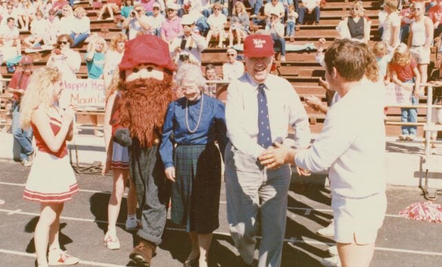 The WSC Mountaineer mascot escorts two honored alumni to the Mountaineer Bowl field during halftime activites, 1987.