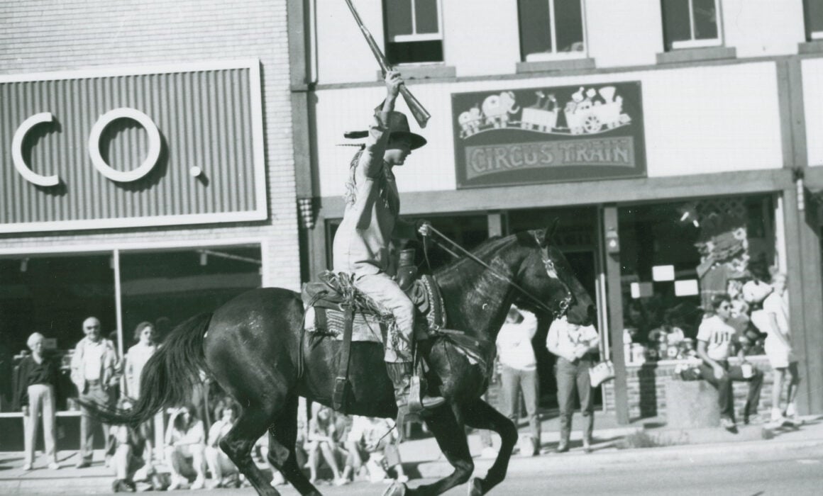The WSC Mountaineer rides horseback on Main Street during the Homecoming parade, circa late 1980s.