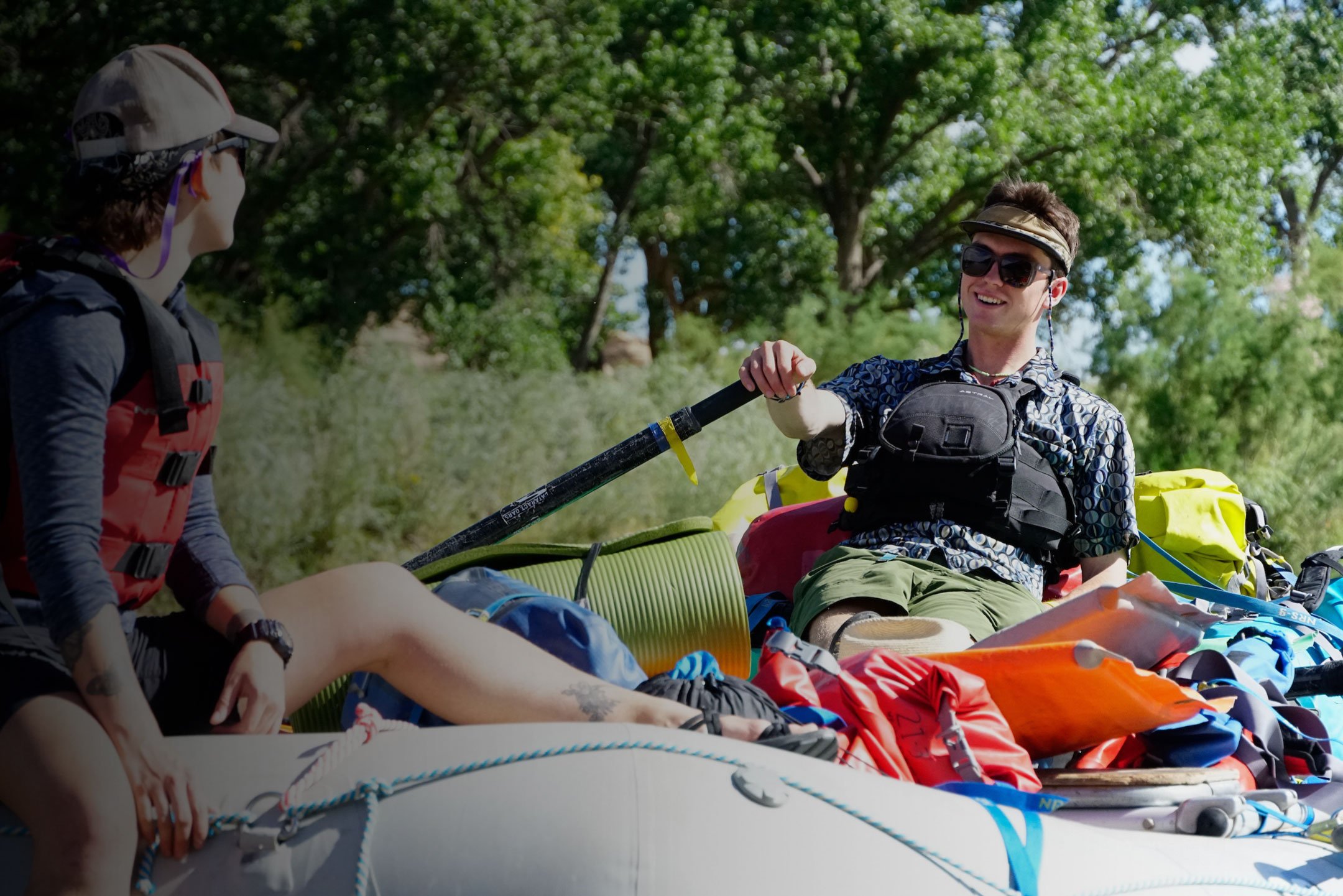 Two male western students with gear on a raft.